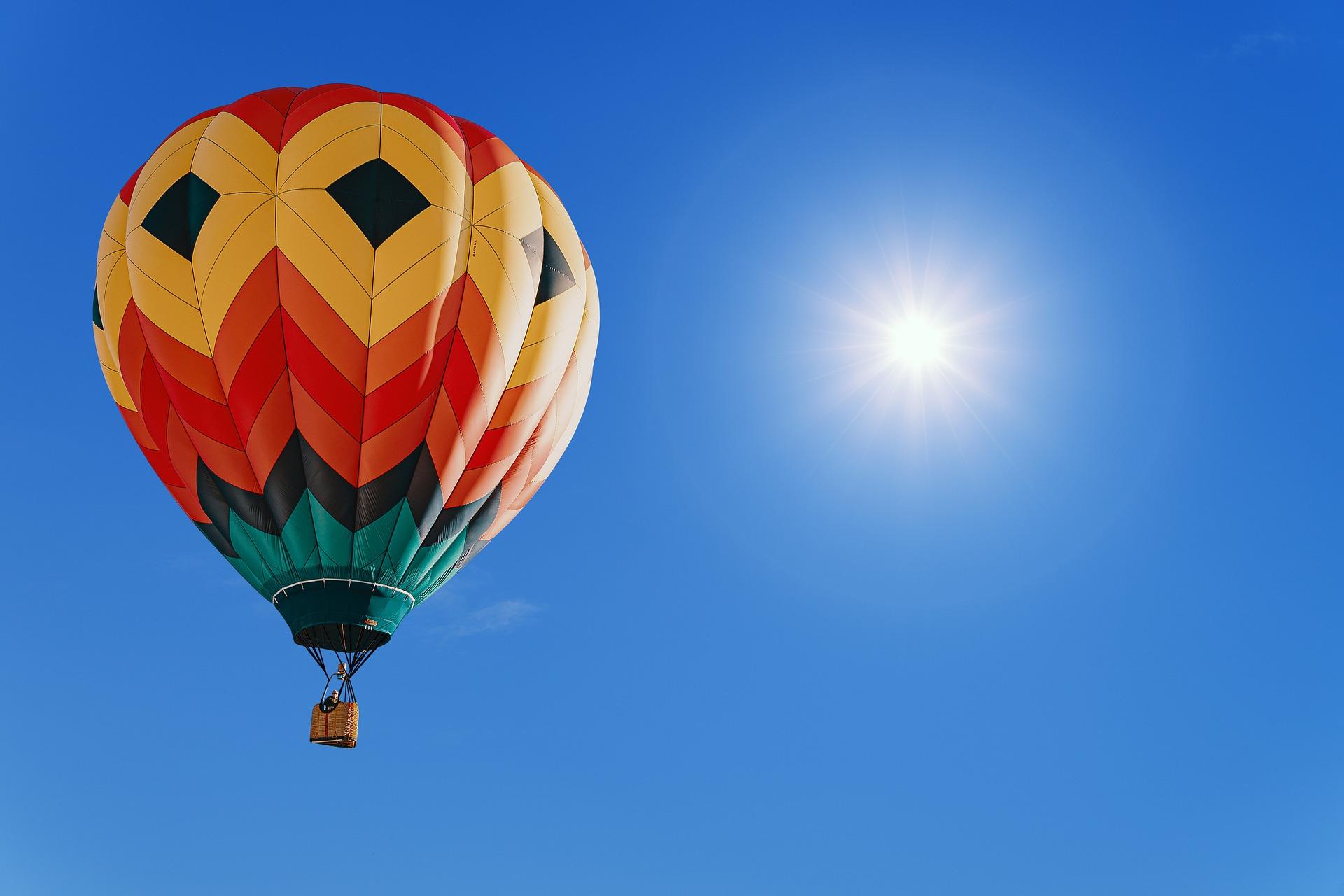 Stimmungsbild zum Beitrag: Es wird ein bunter Heißluftballon vor blauem Himmel abgebildet.
