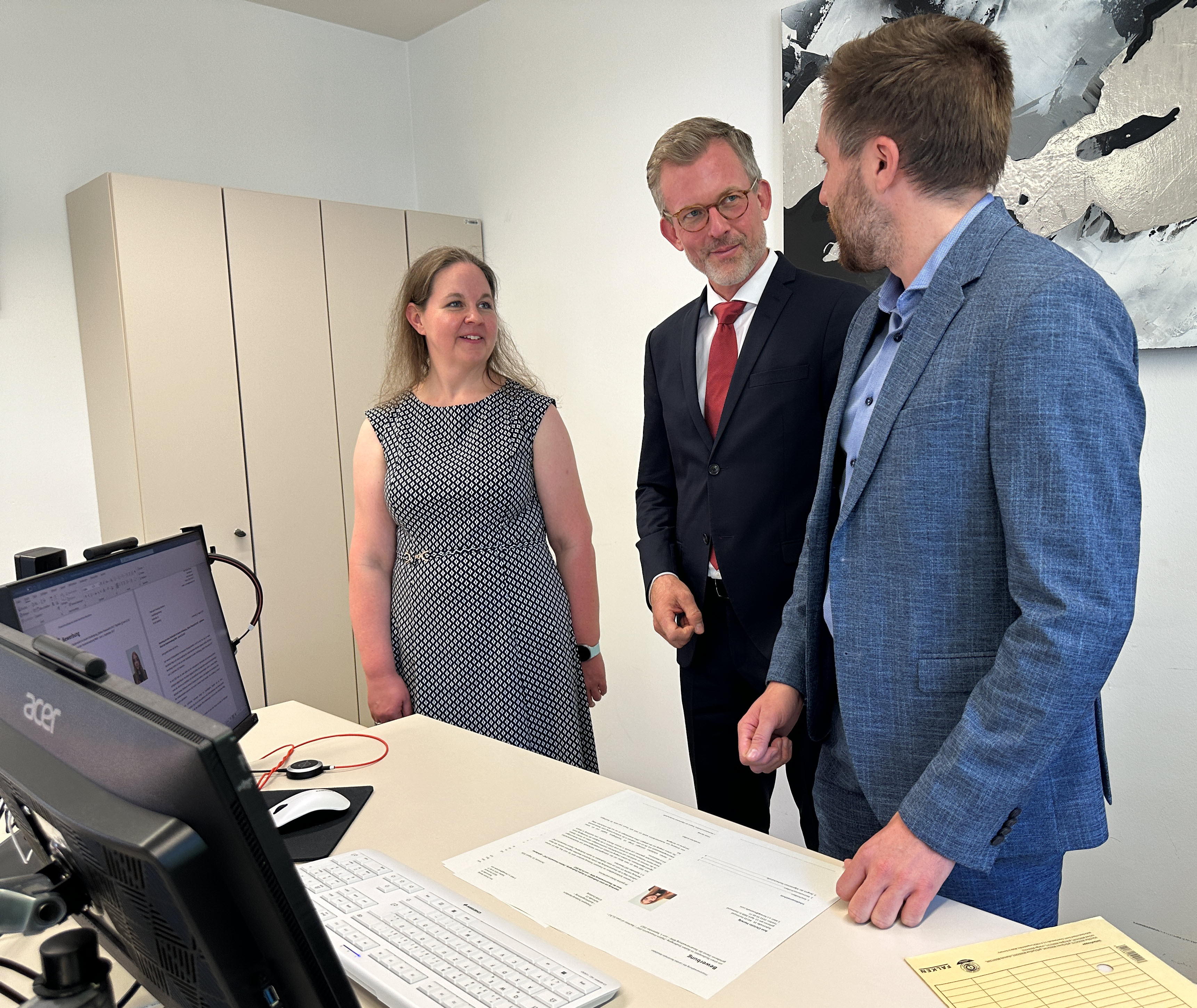 Herr Staatssekretär Dr. Dirk Günnewig (Mitte) im Gespräch mit Personen aus dem Bewerbungauswahlteams des Finanzamts Duisburg-Hamborn . Bartosz Gruszka, stellvertretender Ausbildungsleiter (rechts) und Dienststellenleiterin Ann Christin Herwig (links).
