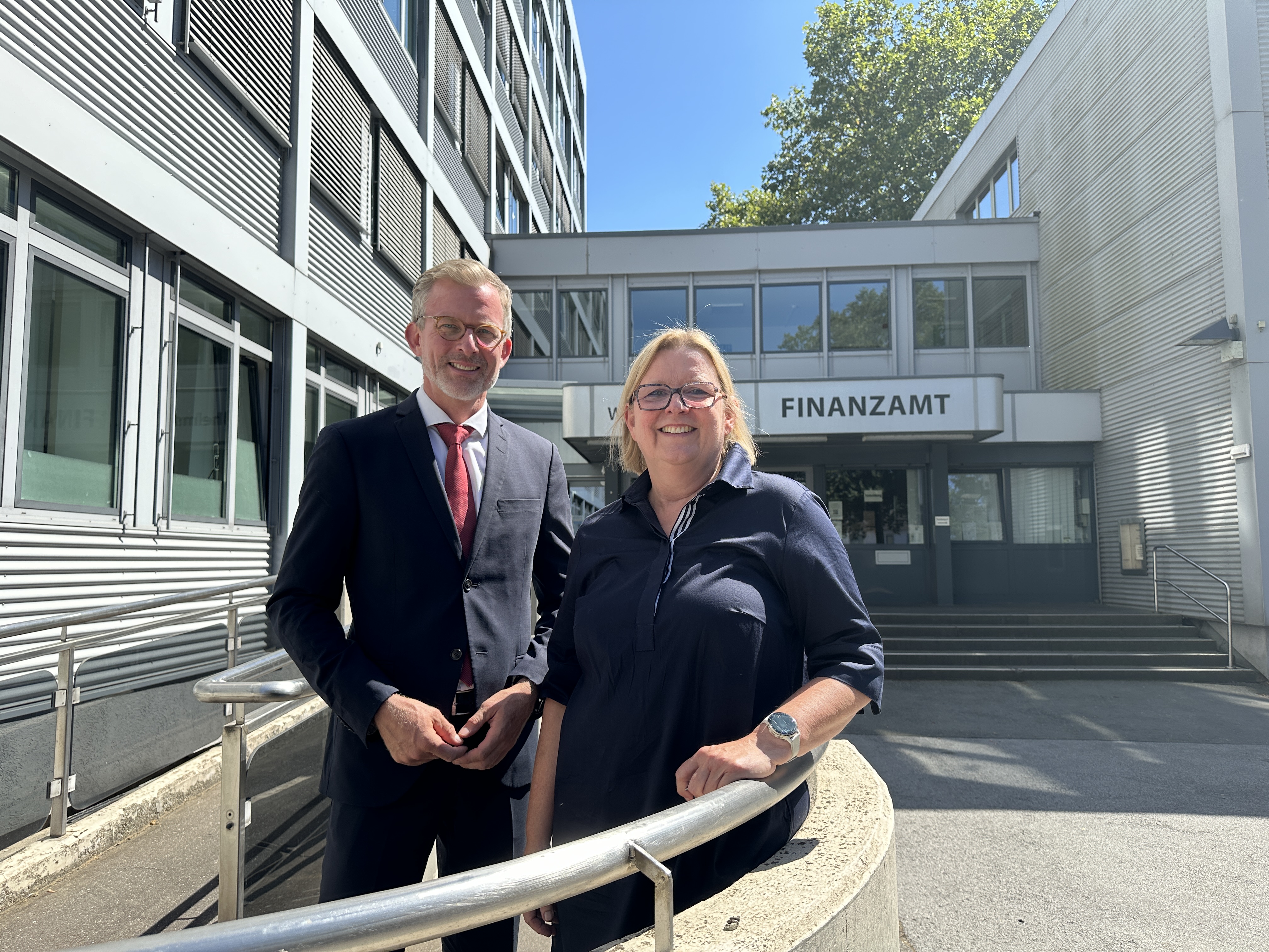 Das Bild zeigt Herrn Staatssekretär Dr. Dirk Günnewig mit Dienststellenleiterin Birgit Höltgen vor dem Finanzamt Mülheim an der Ruhr.