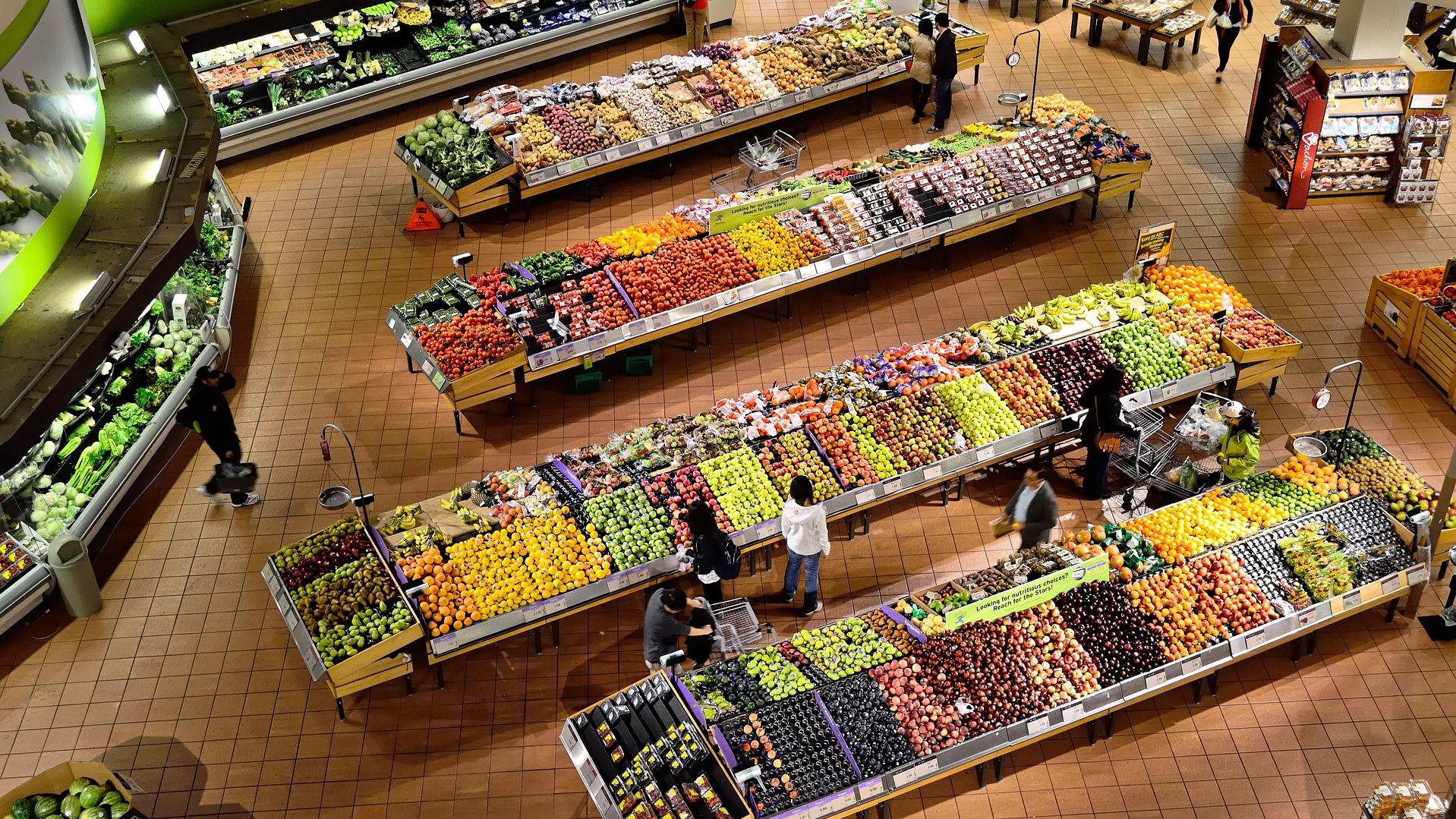 Vogelperspektive auf einen Gemüse- und Obstbereich in einem großen Supermarkt.