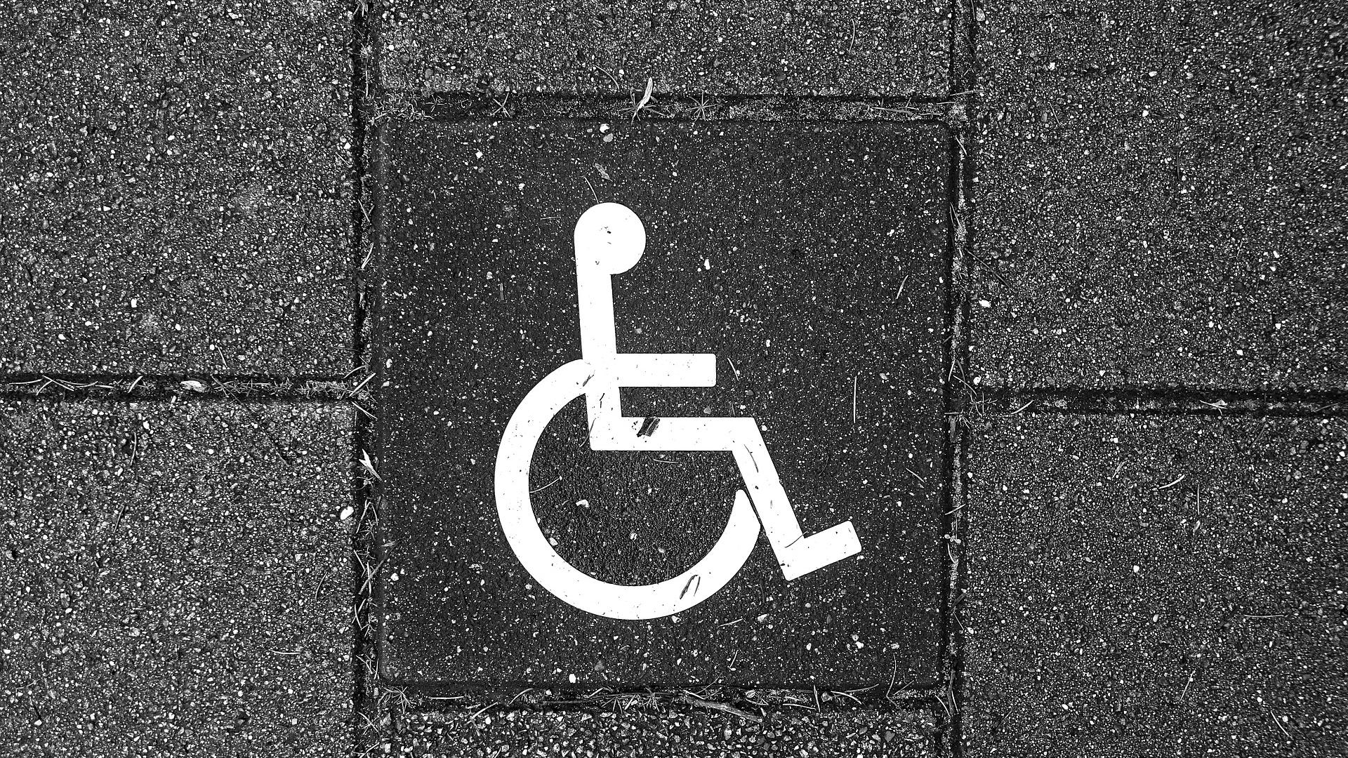 Stimmungsbild zum Beitrag: Es wird ein Rollstuhl-Symbol auf einem Gehwegpflaster abgebildet.