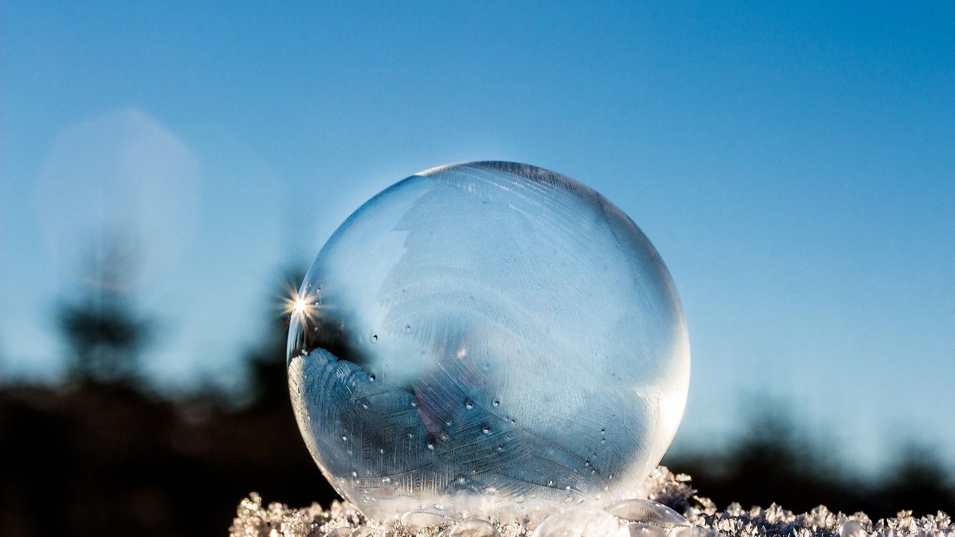 Stimmungsbild zum Beitrag: Es wird eine durchsichtige Eiskugel im Schnee mit blauem Himmel abgebildet.