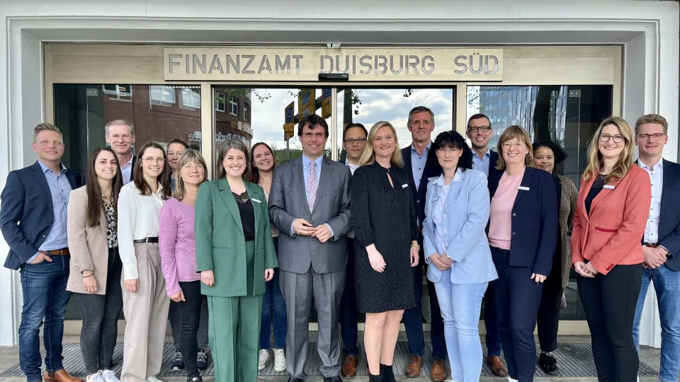 Minister Dr. Marcus Optendrenk (Mitte) wird von der Dienstellenleitung Simone Kockmann (1.Reihe, 4.v.r.) herzlich im Finanzamt Duisburg-Süd begrüßt