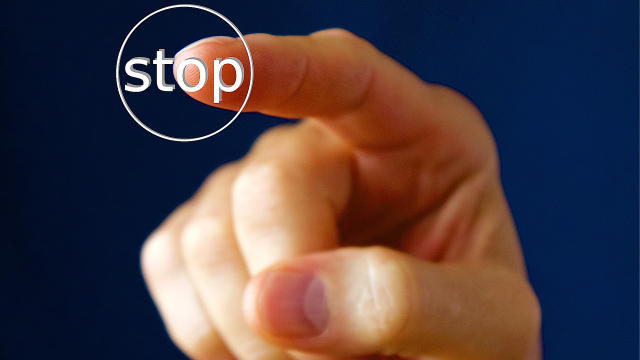 Stimmungsbild zum Beitrag: Ein Zeigefinger drückt auf einen Stop-Knopf.