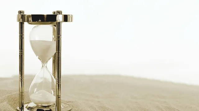 Stimmungsbild zum Beitrag: Es wird eine Sanduhr im Sand abgebildet.