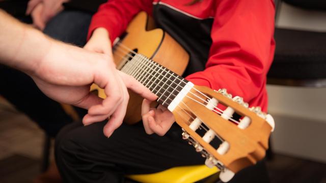 Stimmungsbild zum Beitrag: Es wird ein Kind, das eine Gitarre spielt, abgebildet.