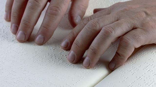 Stimmungsbild zum Beitrag: Es wird eine Person, die in einem Buch Brailleschrift liest, abgebildet.
