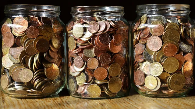 Stimmungsbild zum Beitrag: Es werden drei große Glasbehälter mit Münzen abgebildet.