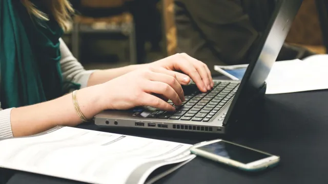 Stimmungsbild zum Thema: Es wird eine Frau sitzend an einem Laptop abgebildet.