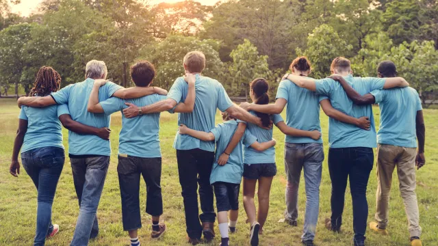 Stimmungsbild zum Beitrag: Es werden neun Personen, die Arm in Arm weggehen, abgebildet.