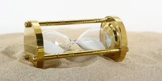 Stimmungsbild zum Beitrag: Es wird eine umgekippte Sanduhr im Sand abgebildet.