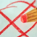 Stimmungsbild zum Beitrag: Es wird ein roter Stift mit einem roten Kreuz auf einem Blatt Papier abgebildet.