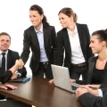 Stimmungsbild zum Beitrag: Sechs Personen im Anzug halten ein Meeting.