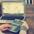 Stimmungsbild zum Beitrag: Es wird eine Frau mit Laptop und Taschenrechner abgebildet.