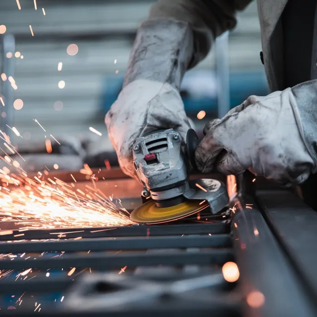 Eine Person in Schutzkleidung arbeitet mit einem Schweißgerät.