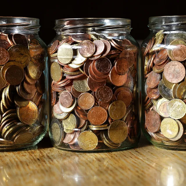 Stimmungsbild zum Beitrag: Es werden drei große Glasbehälter mit Münzen abgebildet.