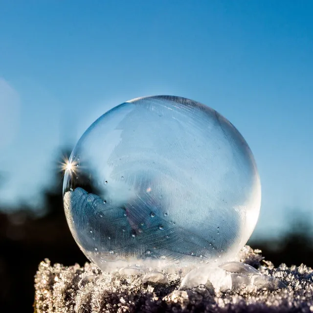 Durchsichtige Eiskugel im Schnee  mit blauem Himmel