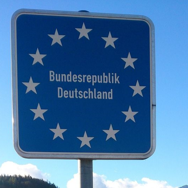 Stimmungsbild zum Beitrag: Es wird ein Straßenschild mit der Aufschrift "Bundesrepublik Deutschland" mit 12 Sternen, die kreisförmig angeordnet sind, abgebildet.