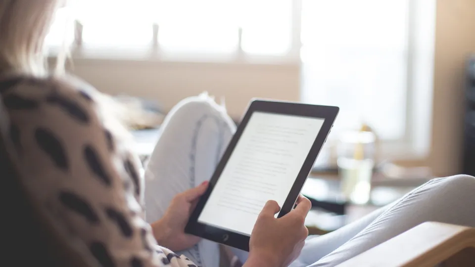 Stimmungsbild zum Beitrag: Ein erwachsenes Kind sitzt mit einem Tablet in der Hand im Stuhl.