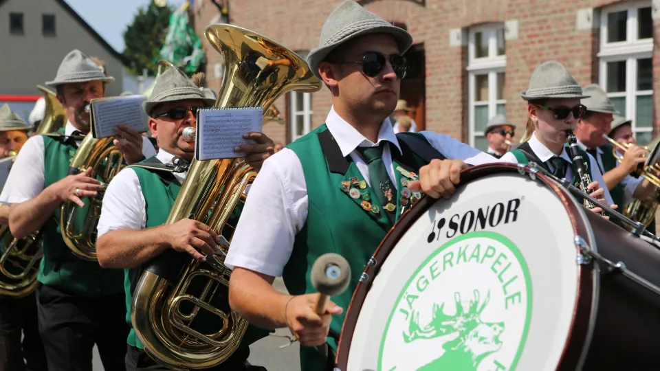 Stimmungsbild zum Beitrag: Es wird eine Kapelle beim Straßenzug in Schützenfest-Kleidung abgebildet.